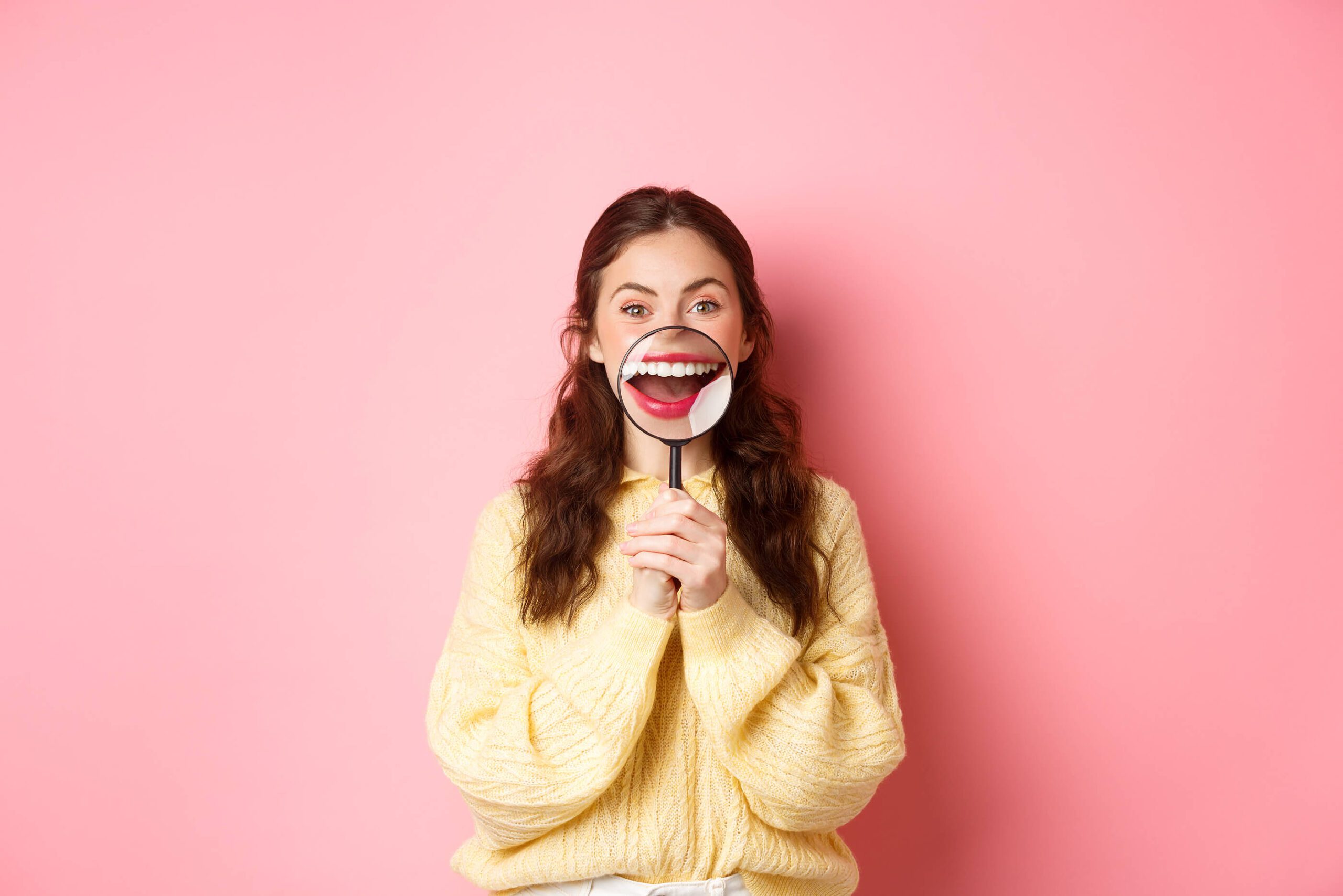 A young woman smiling confidently, showing her teeth after successful Invisalign treatment.